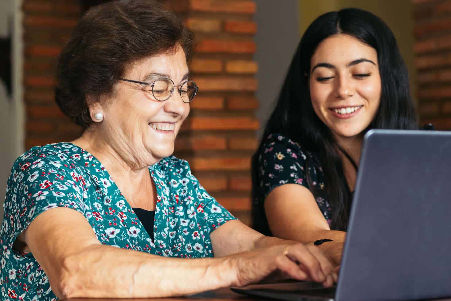 young and older woman smiling while looking at a laptop computer